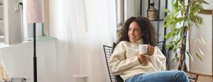 young african american woman sitting in front of a window with coffee